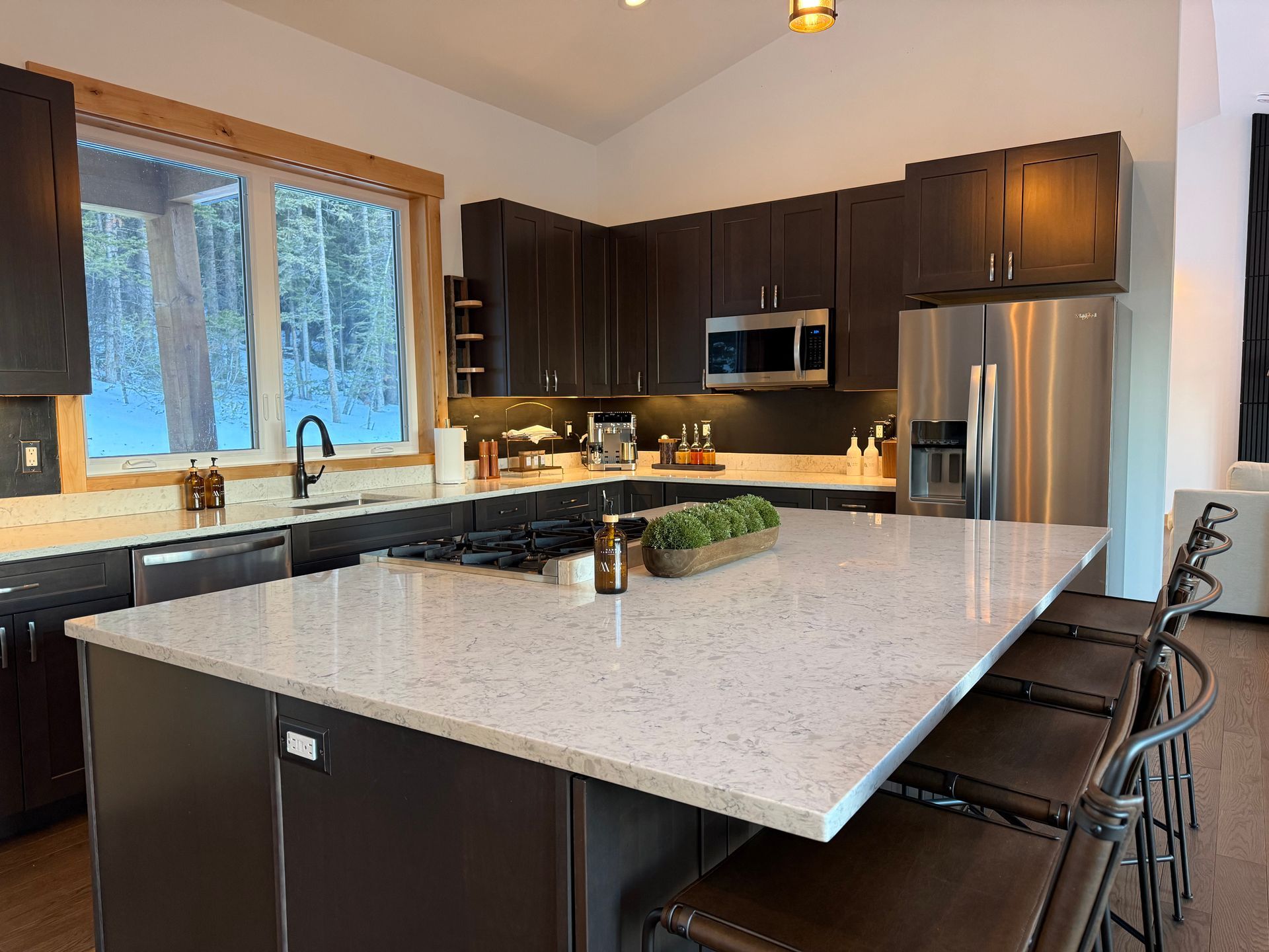Modern kitchen with dark cabinetry, stainless steel appliances, and large island with seating.