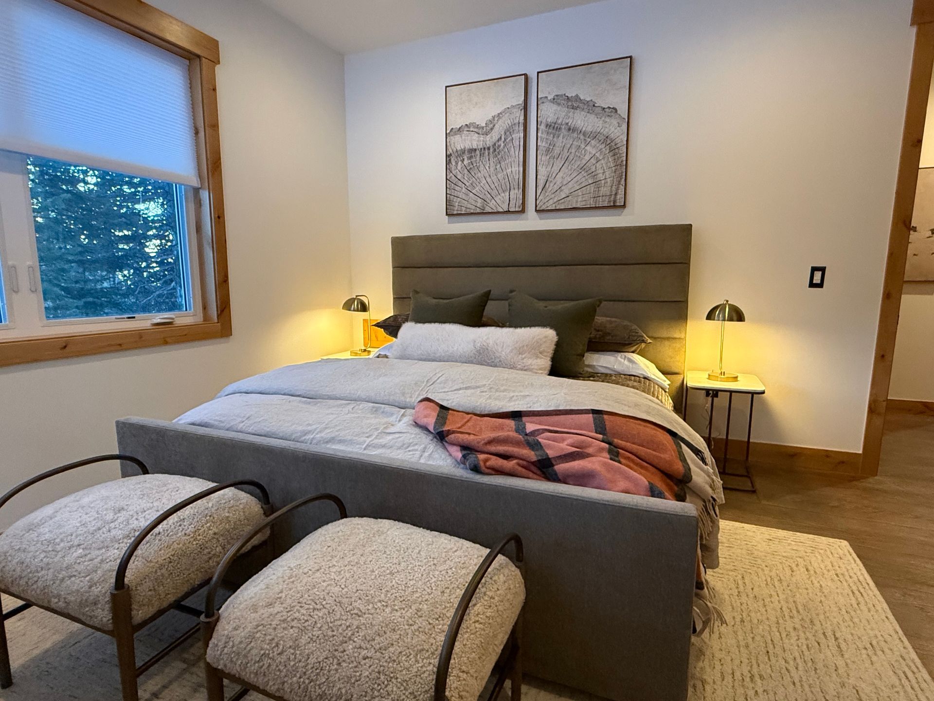 Bedroom with a gray bed, two chairs, and two side tables with lamps. Artwork on the wall above the bed.