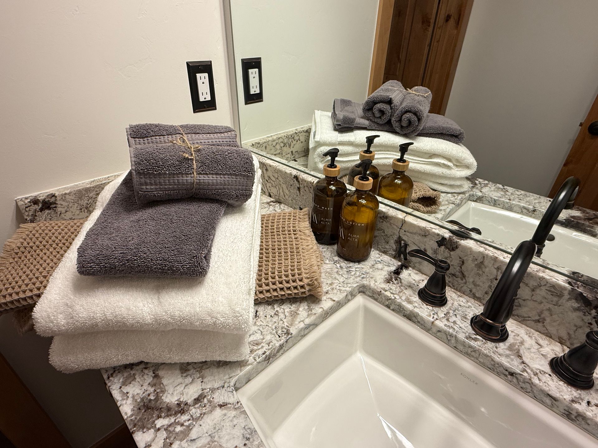Bathroom countertop with stacked towels, bottles, and a sink.