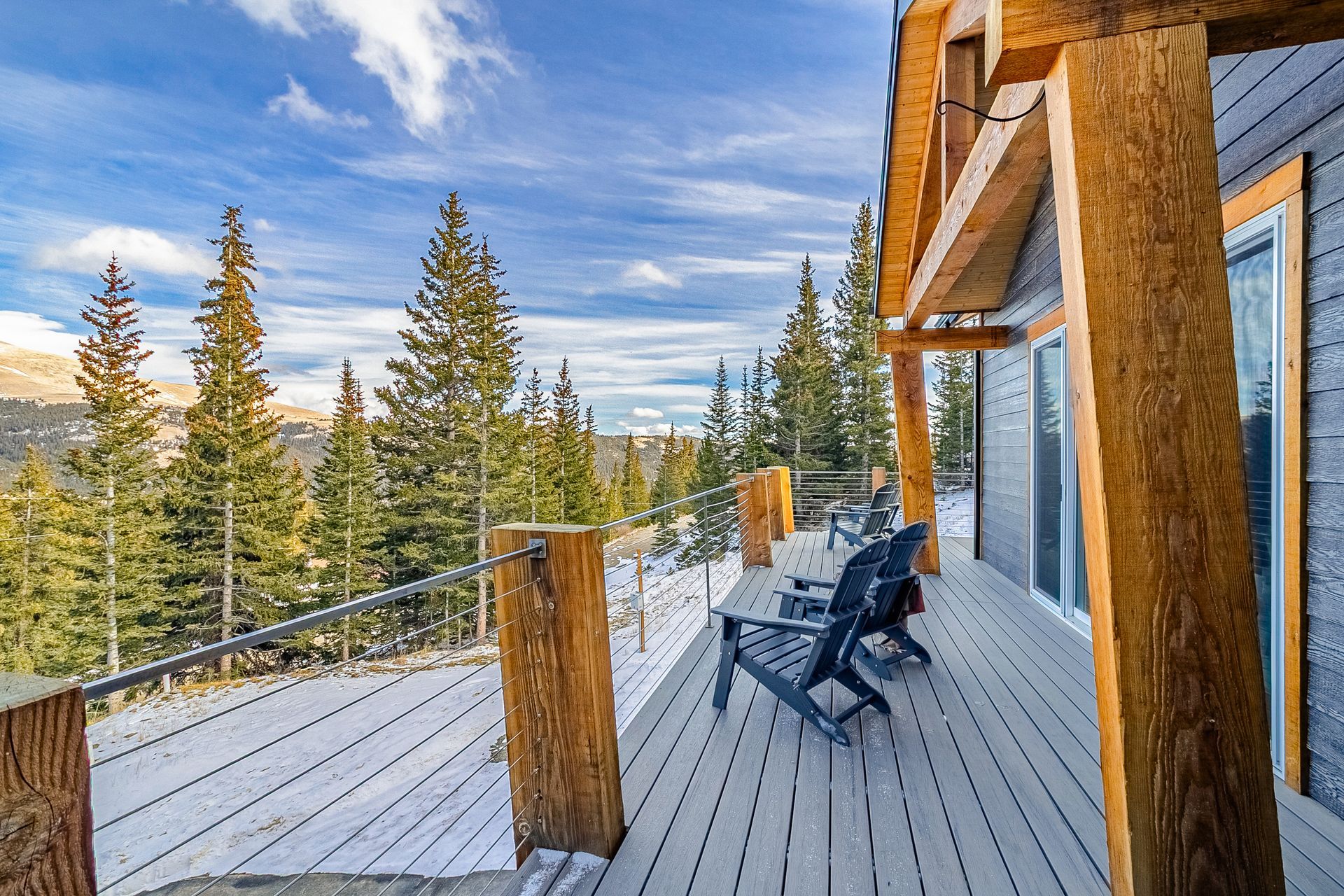 Deck with Adirondack chairs overlooking forest and mountain landscape