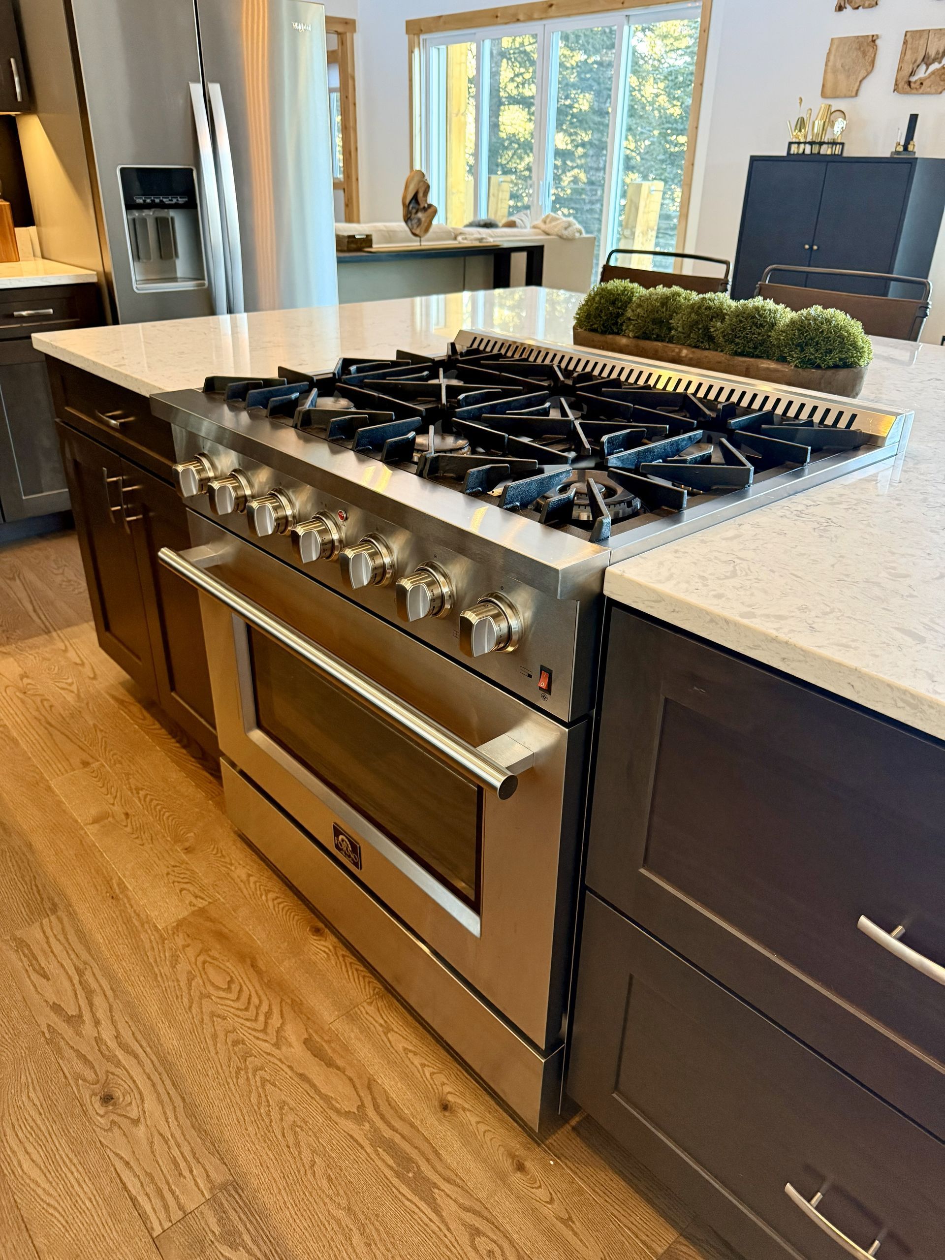 Stainless steel range with oven built into a kitchen island, hardwood floors.