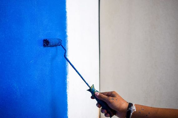 Una persona está pintando una pared azul con un rodillo de pintura.