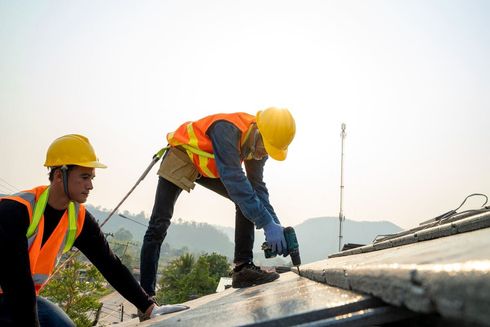 Dos trabajadores de la construcción están trabajando en el tejado de un edificio.