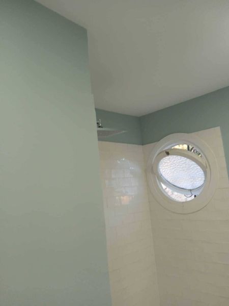 Un baño con una ventana redonda en la pared.