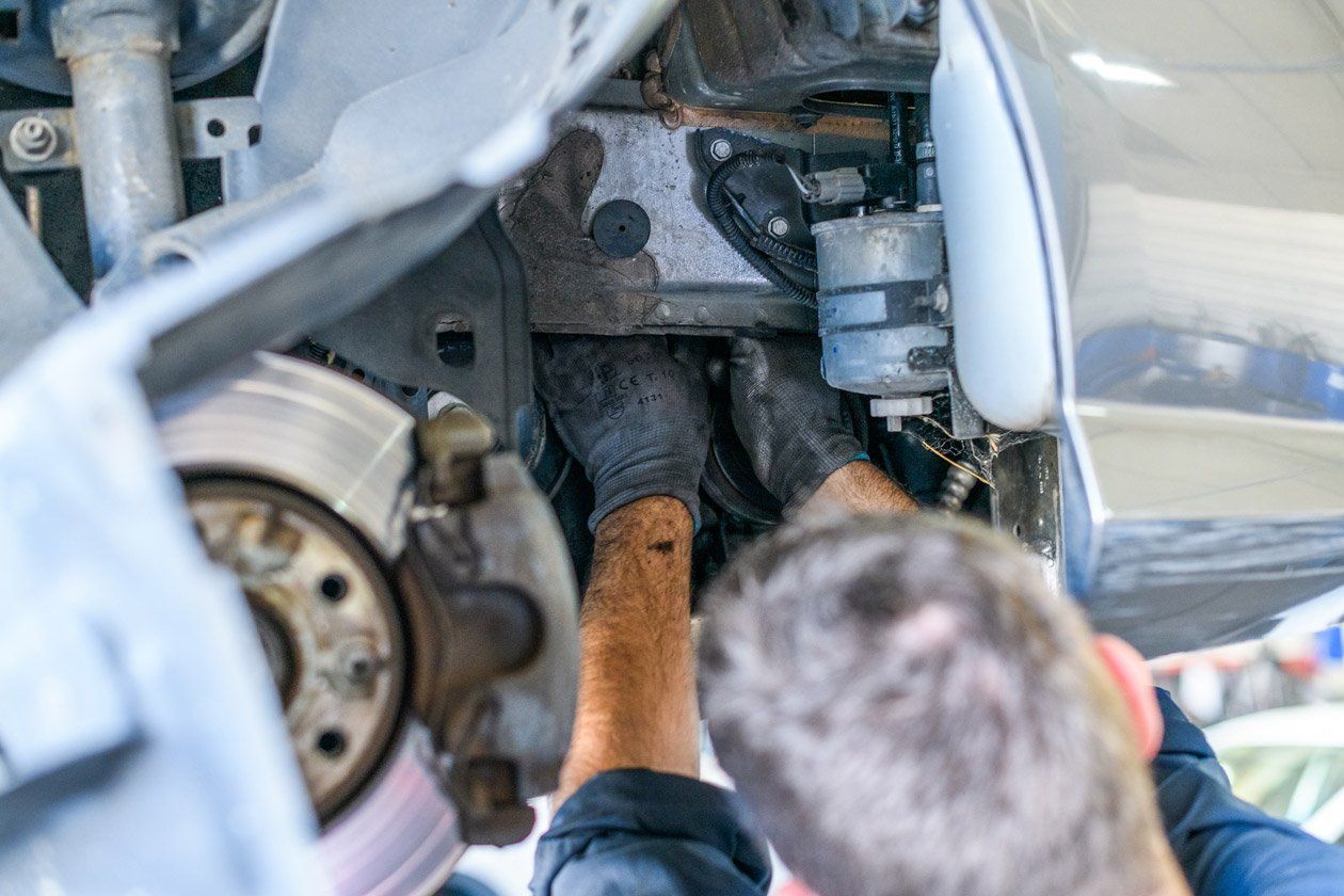 Un professionnel travaillant sur la partie mécanique à côté d'une roue de voiture