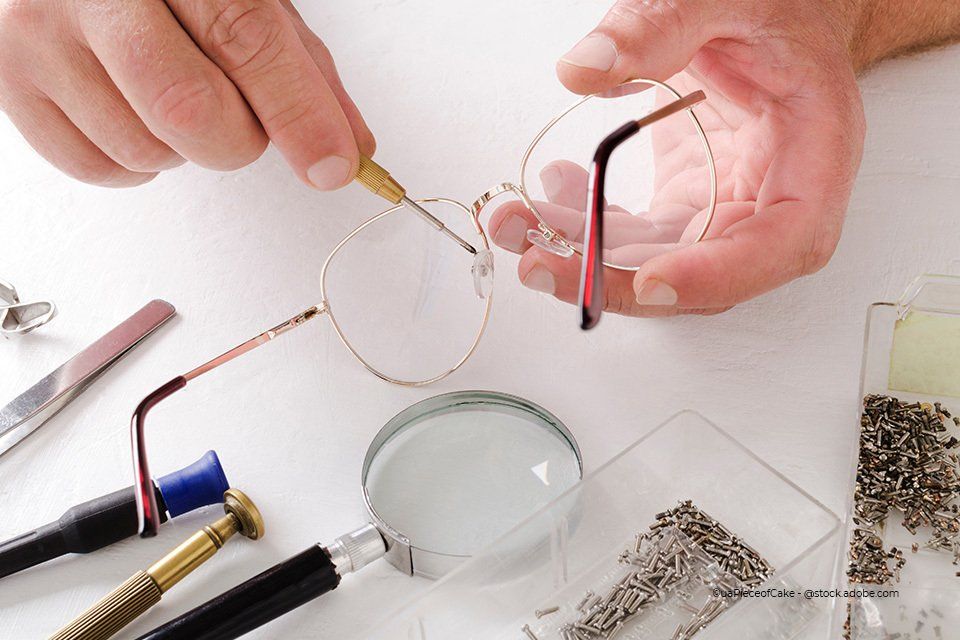 Optikerin von Kaden Carmen-Sylvia Augenoptik Kaden hat Schraubenzieher in der Hand und repariert eine Brille. Daneben liegen weitere Werkzeuge, eine Lupe und Nägel.