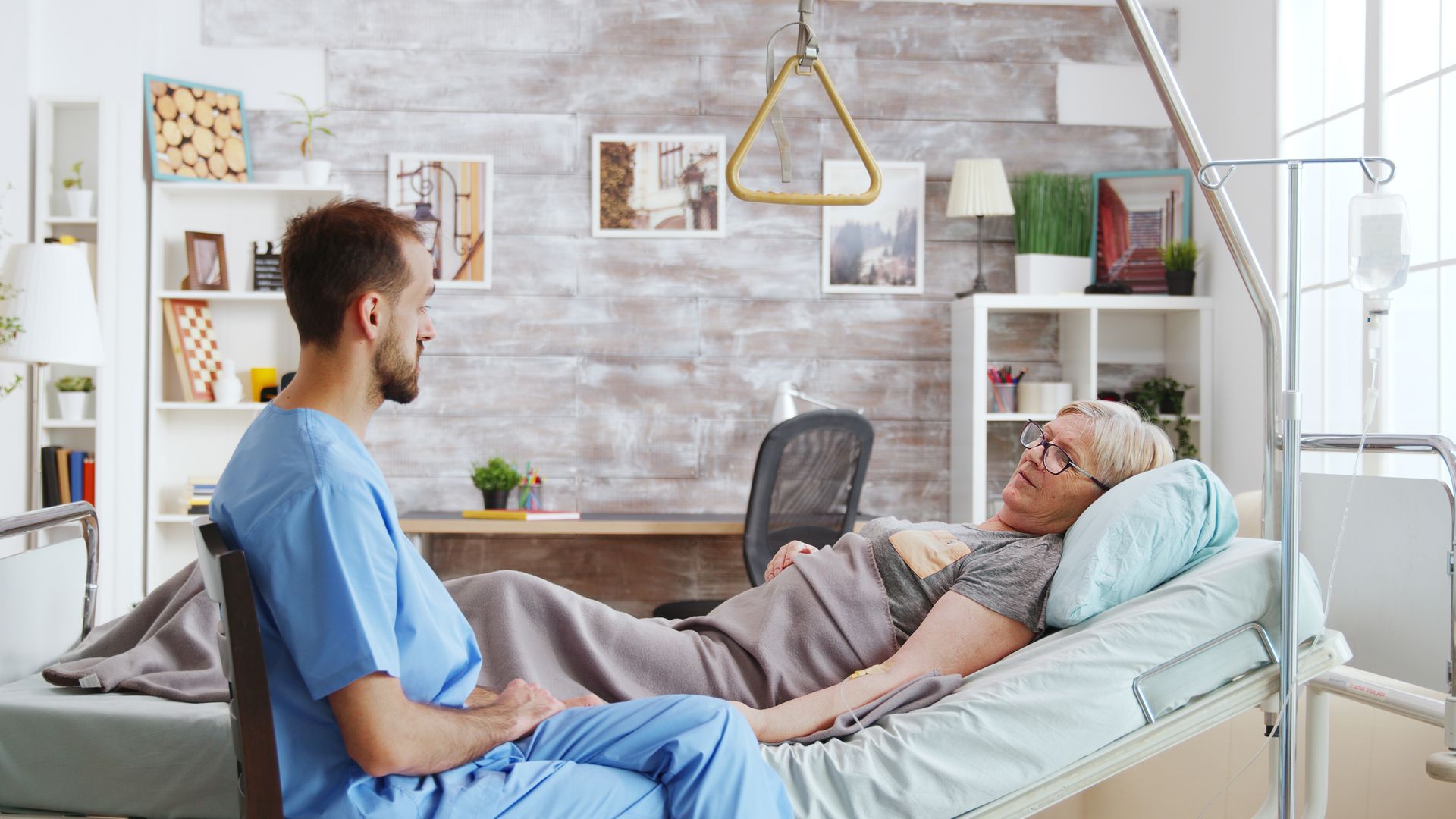 Infirmier surveillant une patiente dans un lit médicalisé