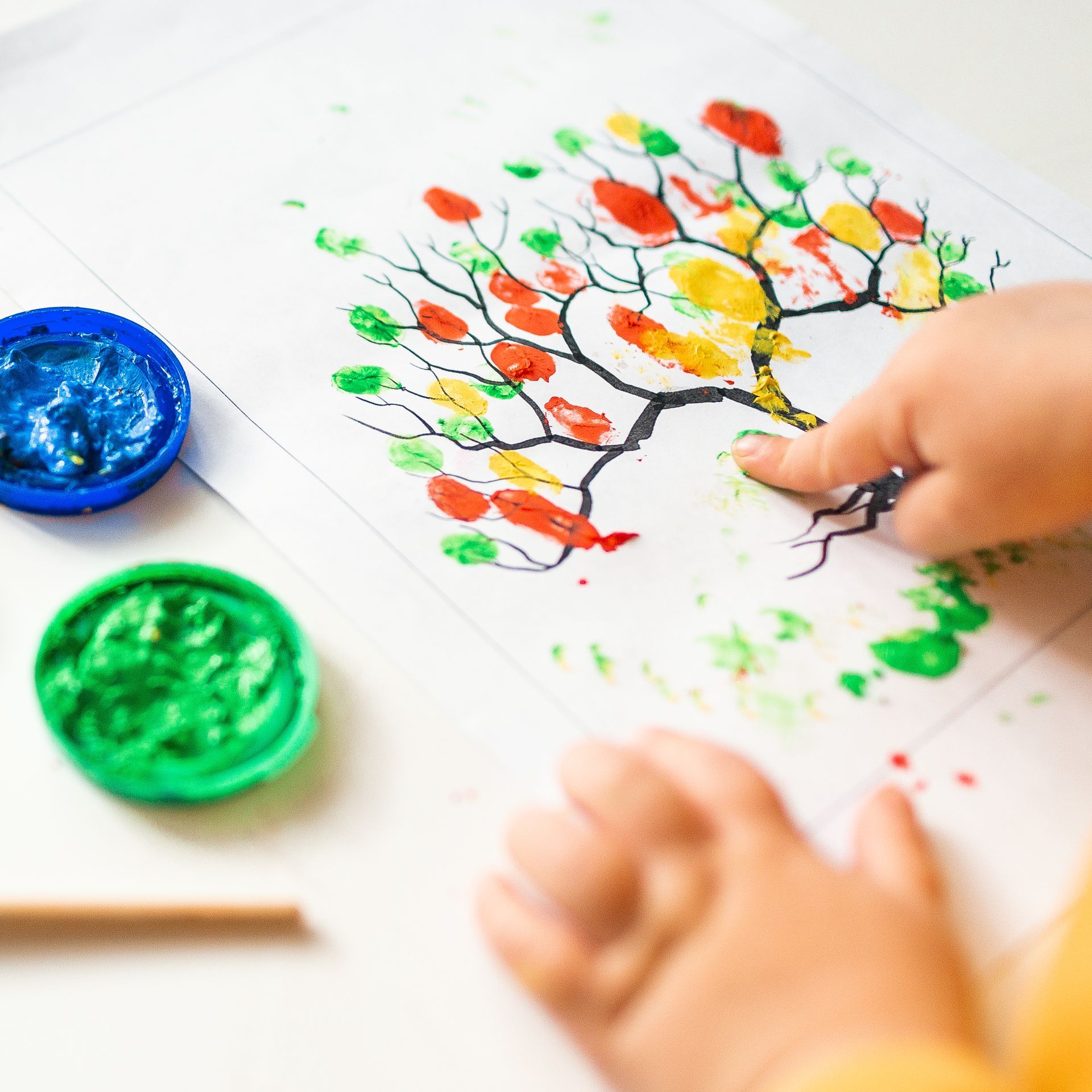 Kind malt einen Baum mit Fingerfarben