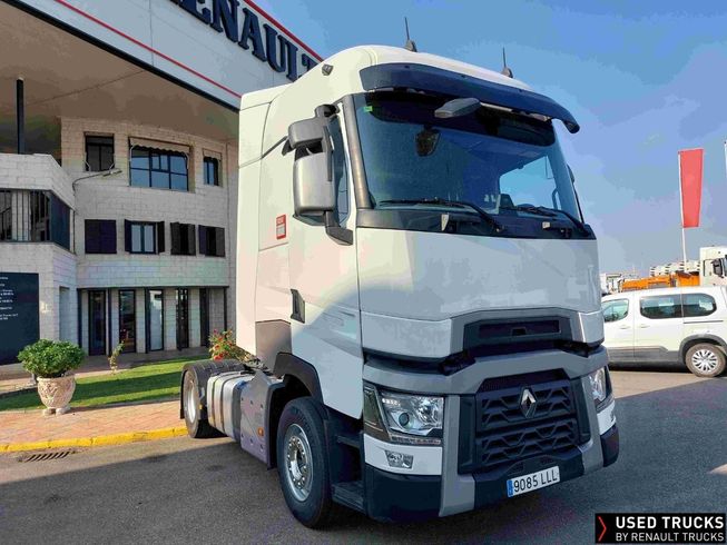 Un camión tractor Renault blanco estacionado frente a un moderno concesionario en un día soleado.