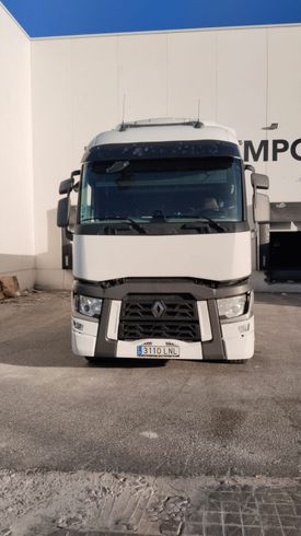 Un camión semirremolque Renault blanco estacionado frente a un edificio blanco en un día despejado.