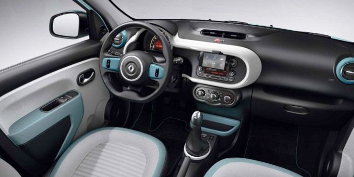 Intérieur d'une voiture turquoise et blanche, avec tableau de bord et volant noirs.