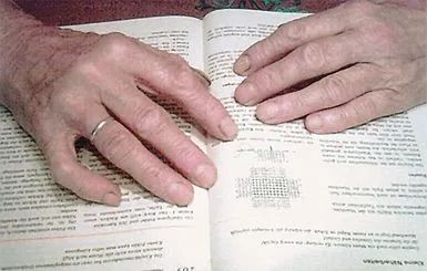 Hände einer älteren Person liegen auf einem Buch