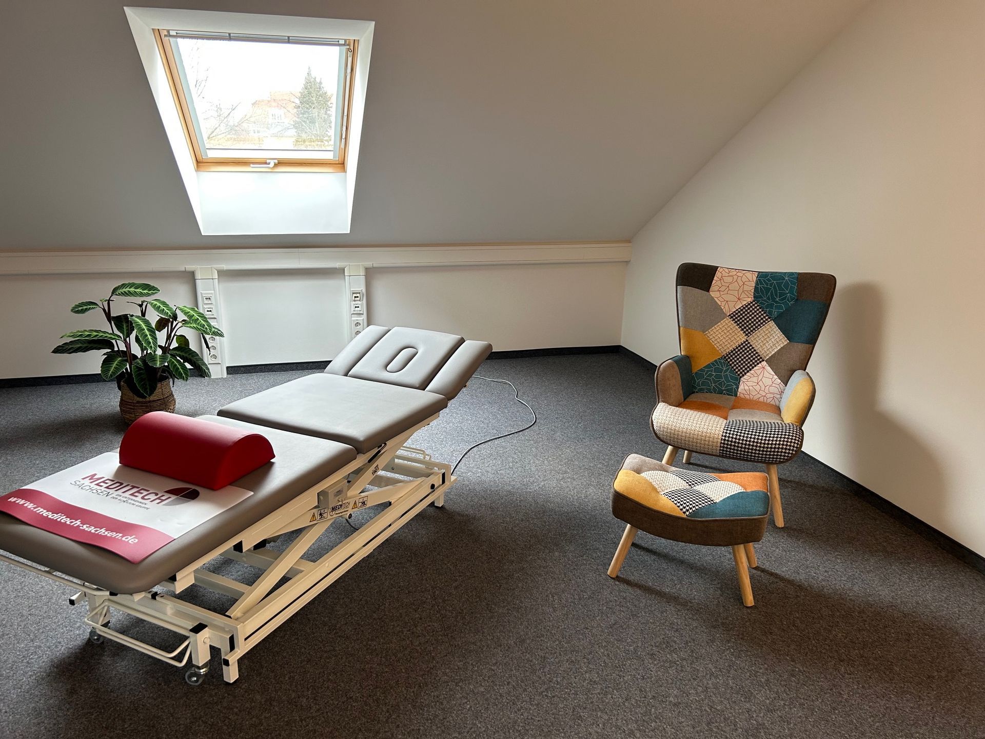 Eine Liege und ein Stuhl in einem Behandlungszimmer mit Teppich