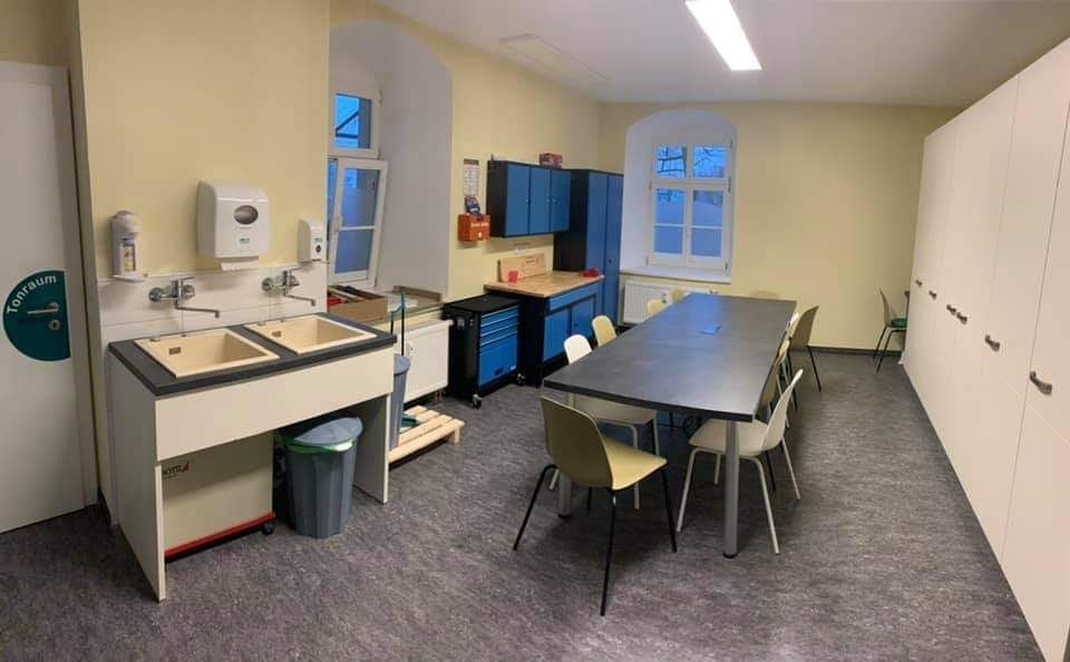 Ein Besprechungsraum mit zwei Spülen und einem langen Tisch mit 5 Stühlen