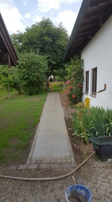 ein Gehweg , der zwischen zwei Häusern in einem Garten führt .