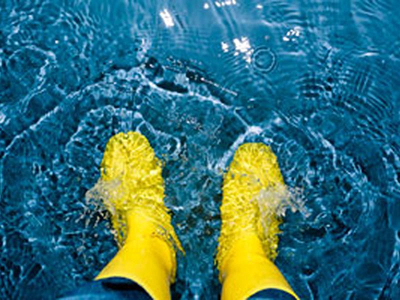 eine Person in gelben Gummistiefeln steht im Wasser .