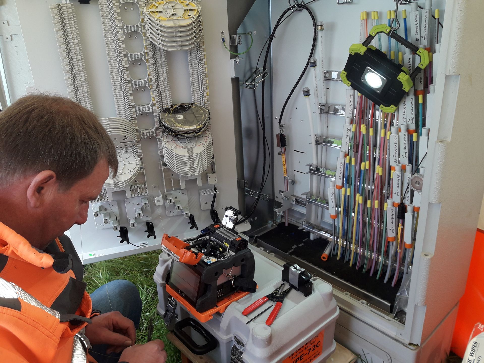 ein Mann arbeitet in einem elektrischen Gehäuse mit einer orangefarbenen Maschine