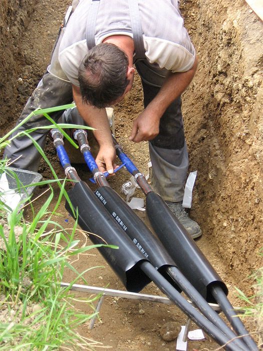 ein Mann arbeitet an einem Kabel in einem Graben