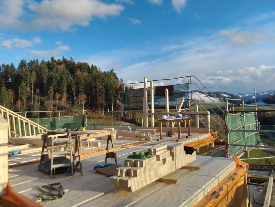 Baustelle mit Holzgerüsten und Betonblöcken neben einer Brücke unter blauem Himmel