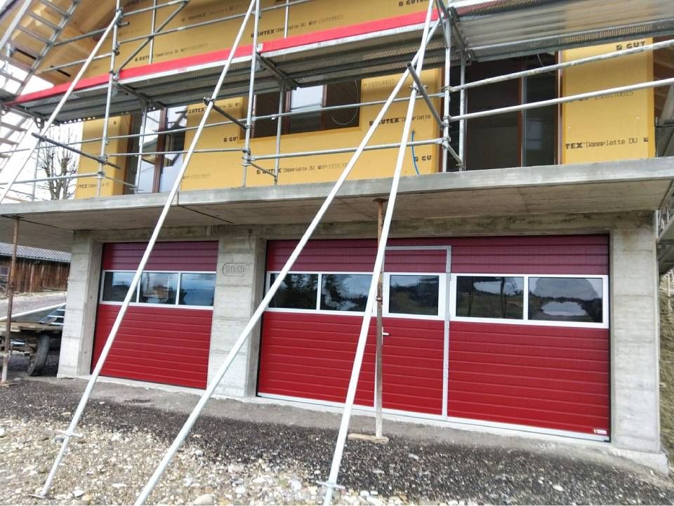 Gerüst um das gelbe Gebäude mit den roten Garagentoren im Bau