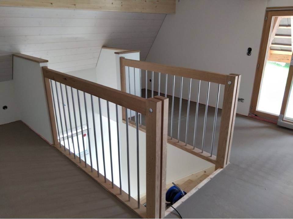 Treppenhaus im Obergeschoss mit Holzgeländer und weissen Balustern neben einer Tür nach draussen