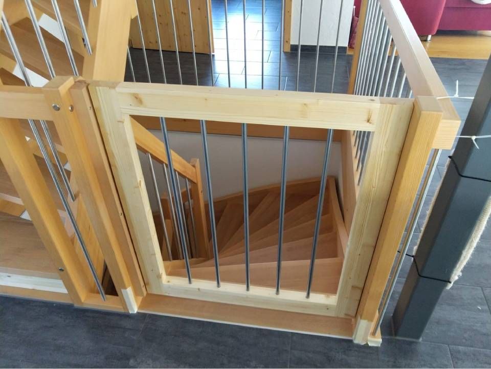 Holztreppe mit einem Kindersicherheitsgitter, das den oberen Treppenabsatz absperrt