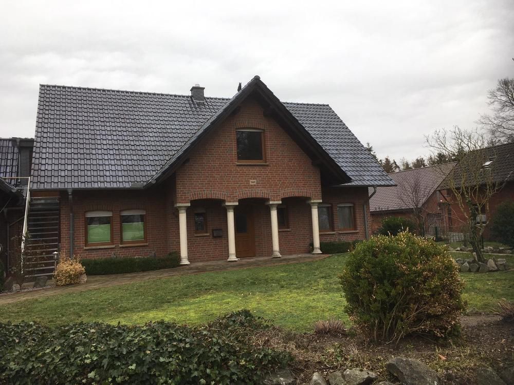 Ein großes Backsteinhaus mit blauem Dach und Säulen