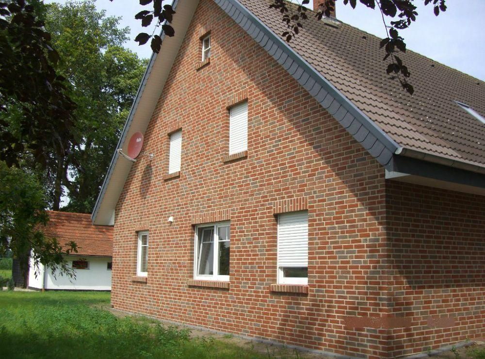 Ein Backsteinhaus mit grauem Dach und weißen Fenstern