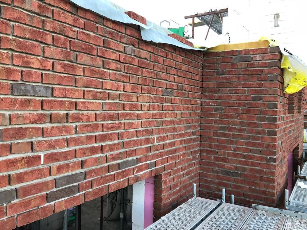 An der Seite eines Gebäudes wird eine Ziegelmauer errichtet.