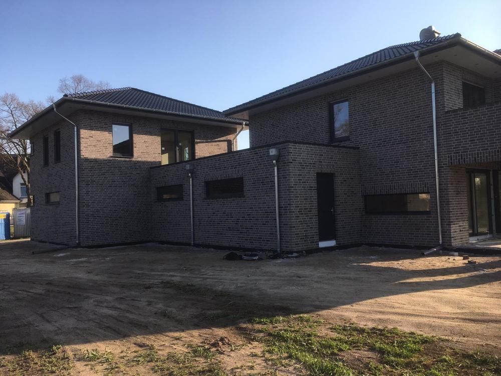 Ein großes Backsteinhaus mit vielen Fenstern steht auf einem Feld.