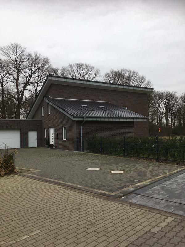 Ein Backsteinhaus mit Garage und davor liegender Einfahrt.