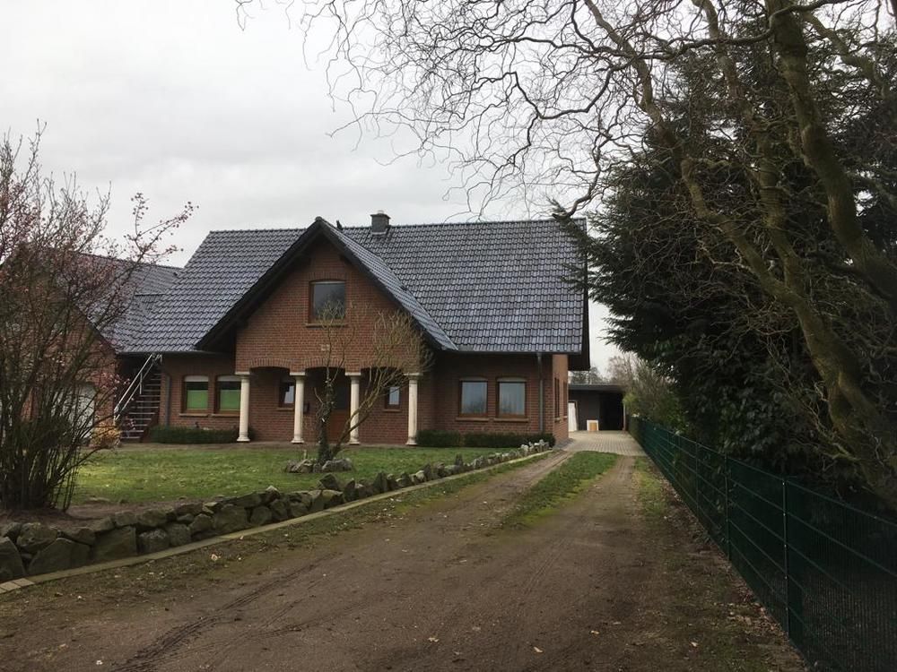 Ein großes Backsteinhaus mit blauem Dach und einer Auffahrt, die dorthin führt.
