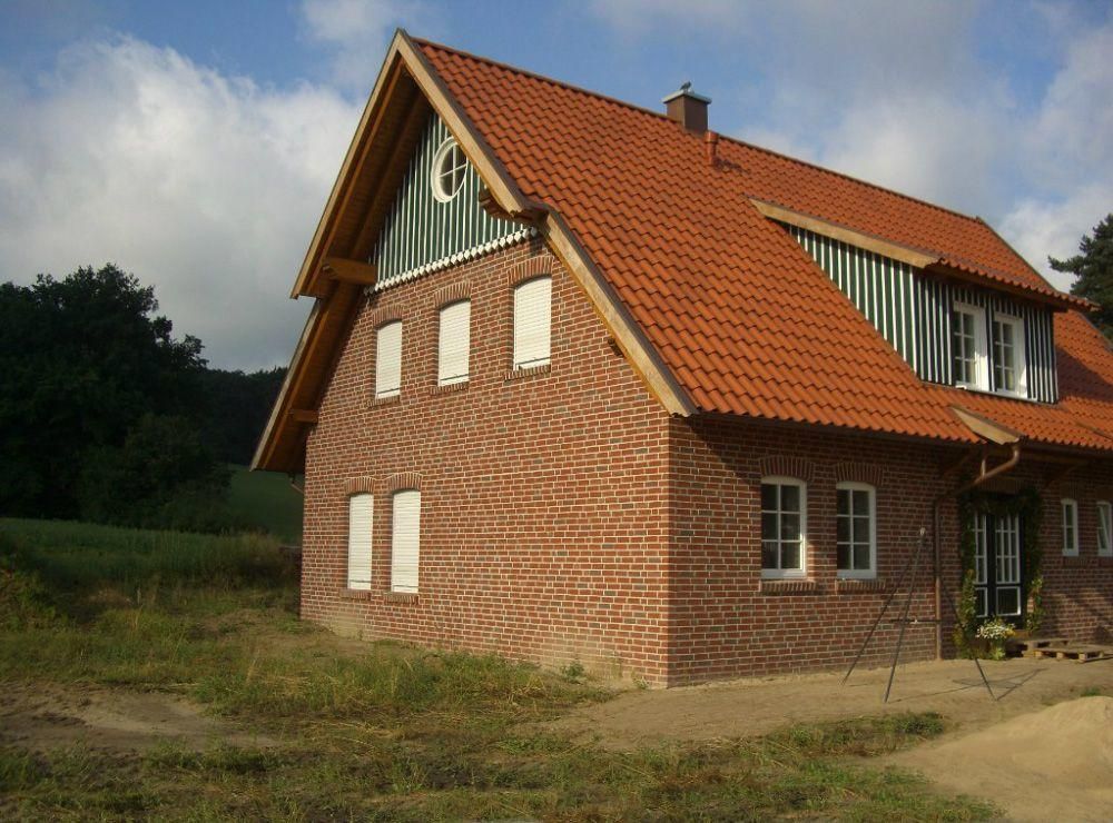 Ein Backsteinhaus mit rotem Dach und weißen Fenstern