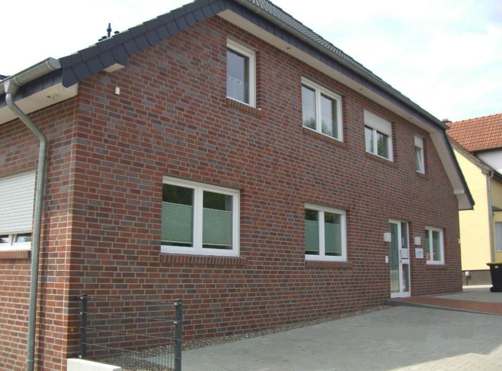 Ein Backsteingebäude mit weißen Fenstern und einem schwarzen Dach