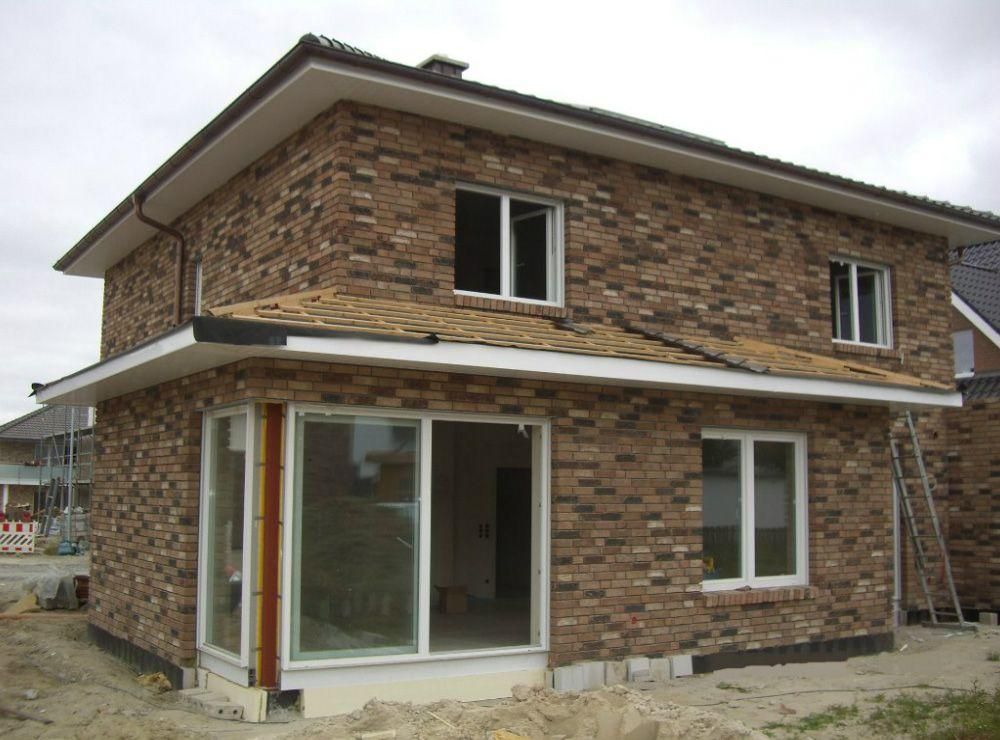 Ein Backsteinhaus mit weißen Fenstern und einem Dach