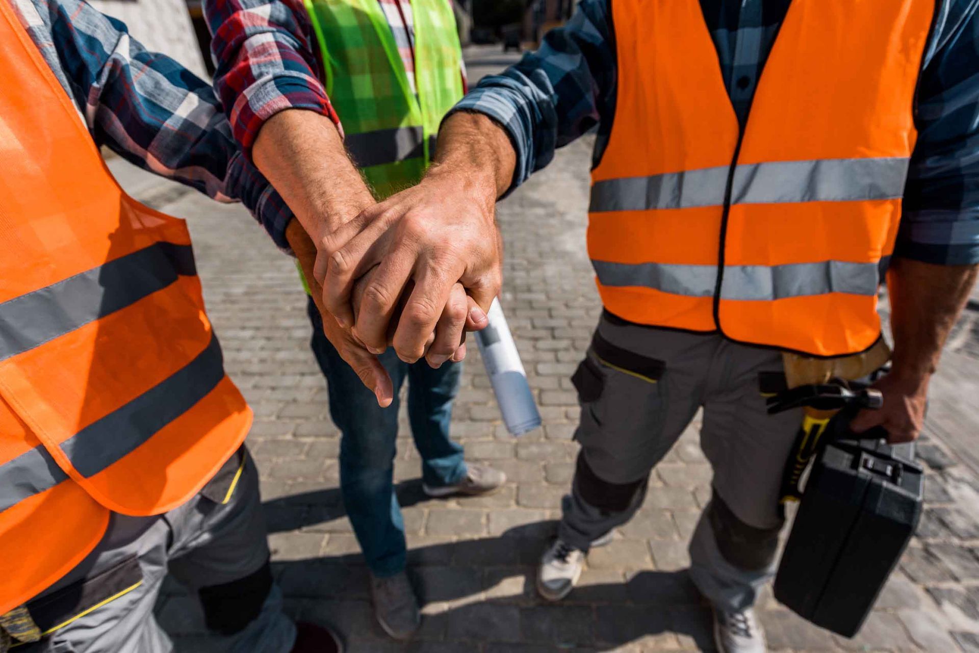 Un grupo de trabajadores de la construcción están juntando sus manos.
