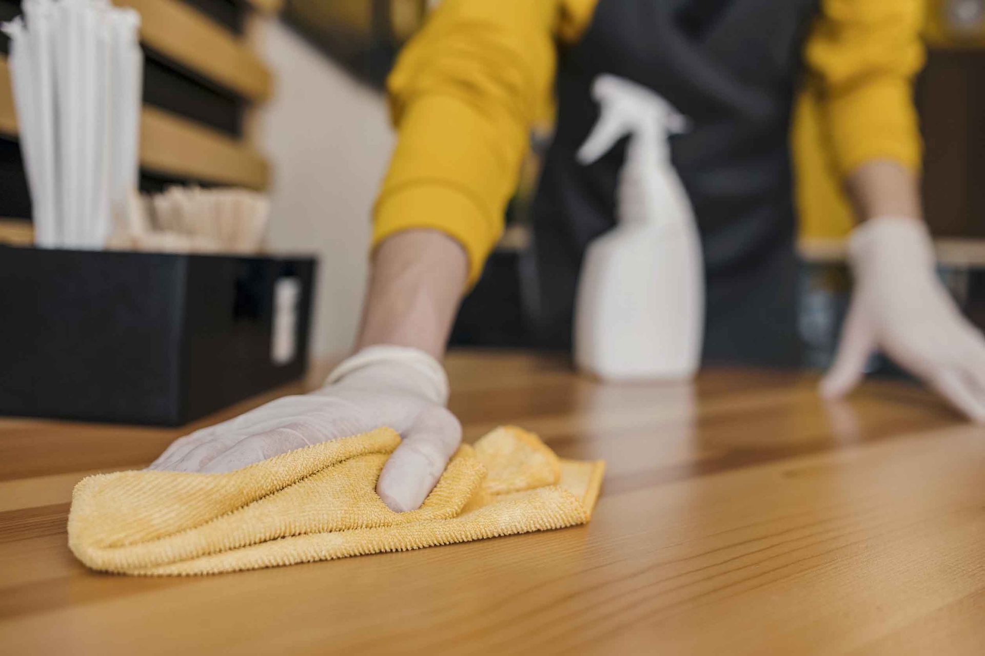 Una persona está limpiando una mesa de madera con un paño.