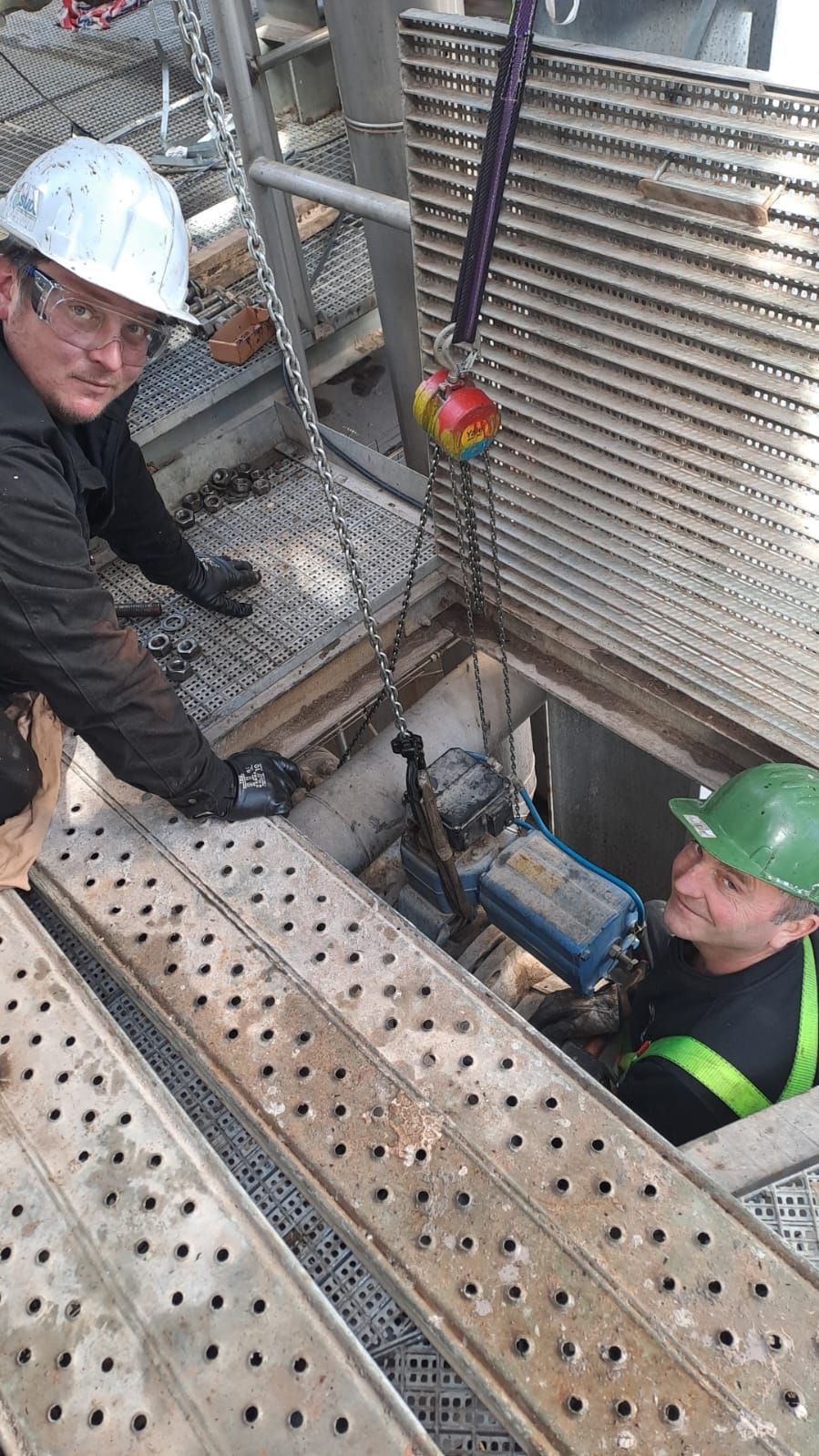 Dos hombres están trabajando en una máquina en una tapa de alcantarilla.