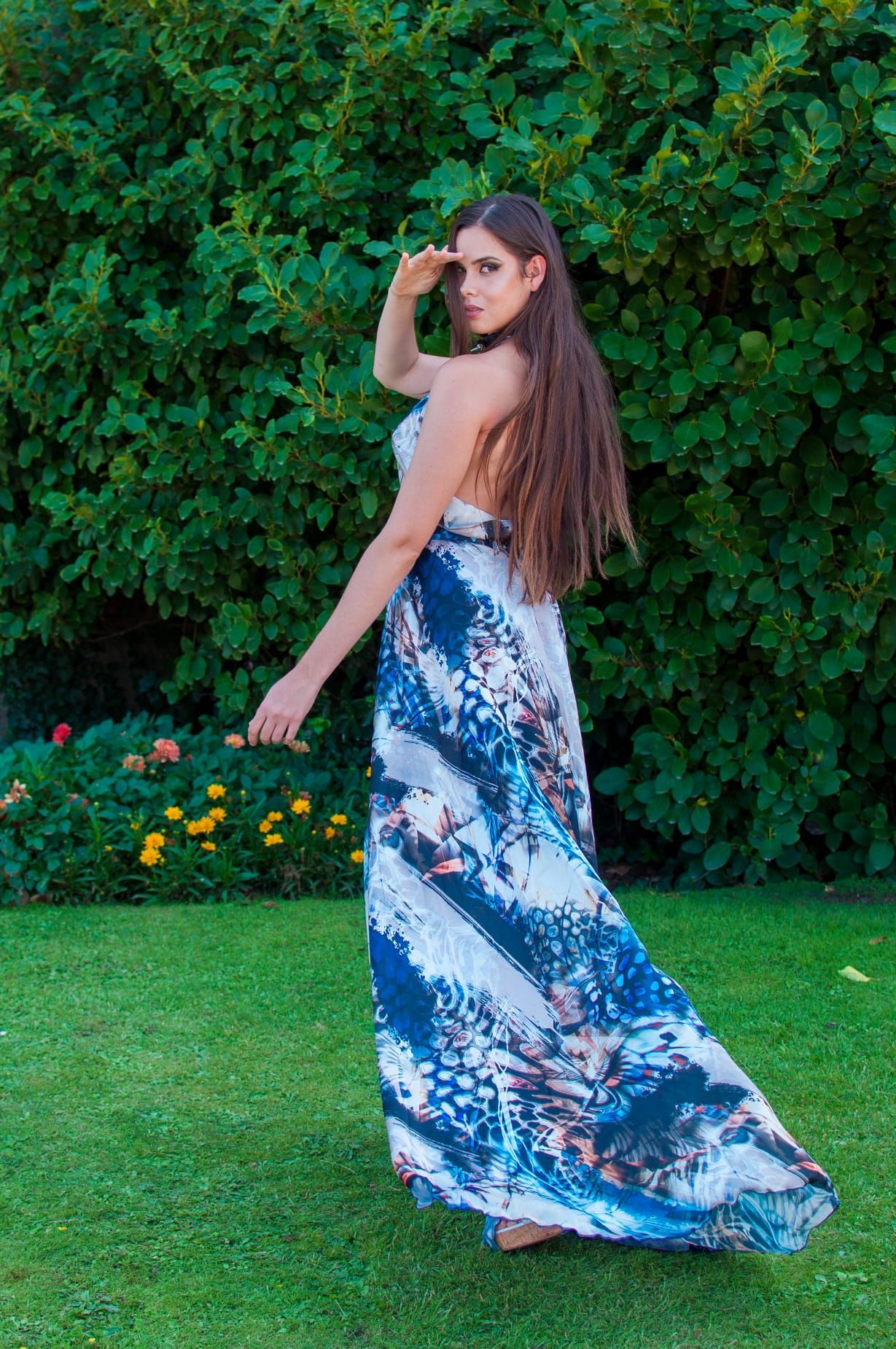 Una mujer con un vestido azul y blanco está parada en la hierba.