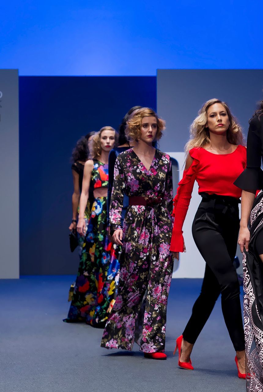 Un grupo de mujeres camina por una pasarela en un desfile de moda.