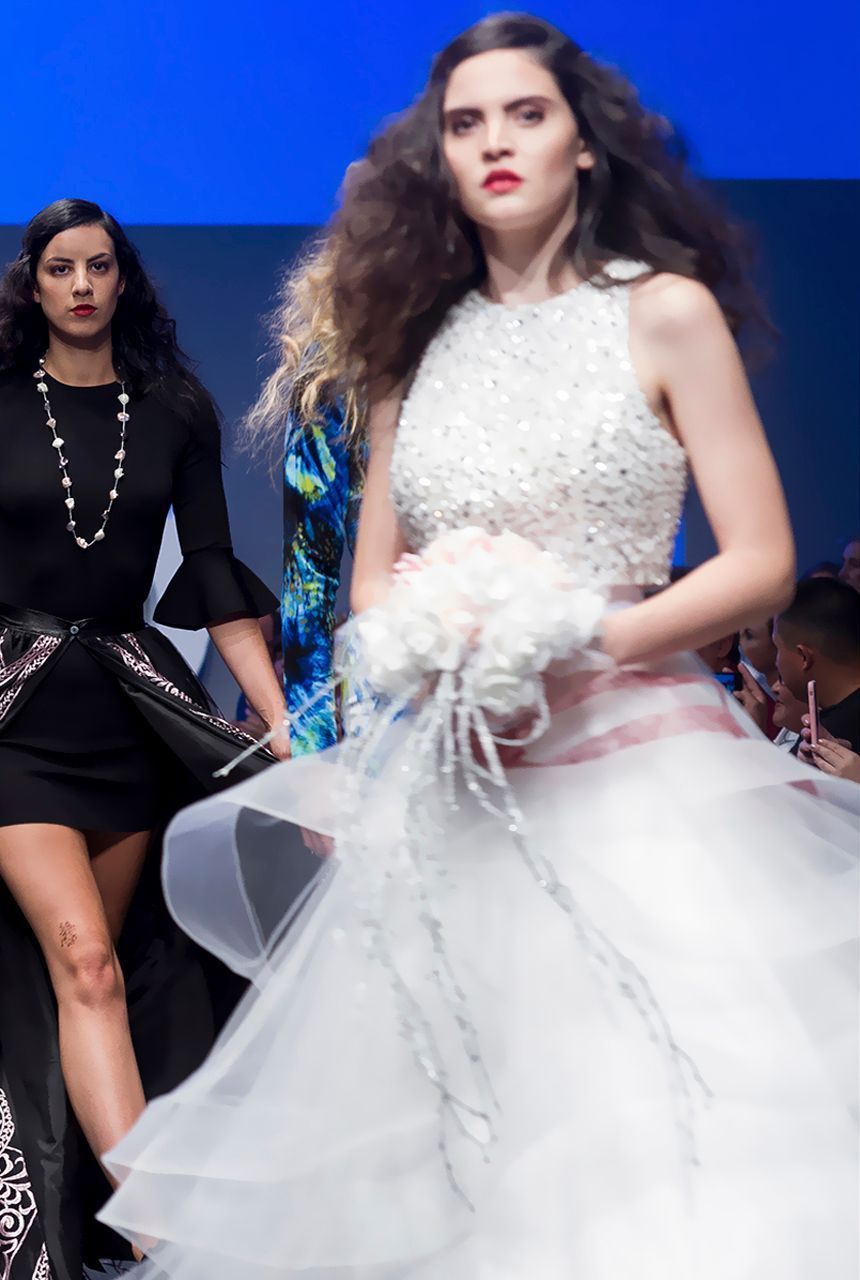 Una mujer con un vestido blanco camina por una pasarela.