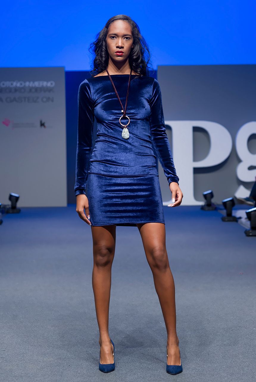 Una mujer con un vestido azul camina por una pasarela.