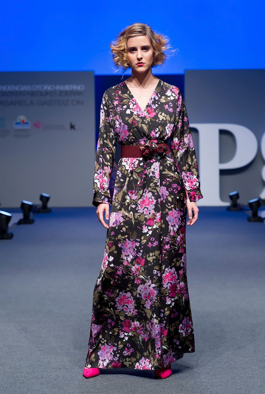 Una mujer camina por una pasarela con un vestido floral.