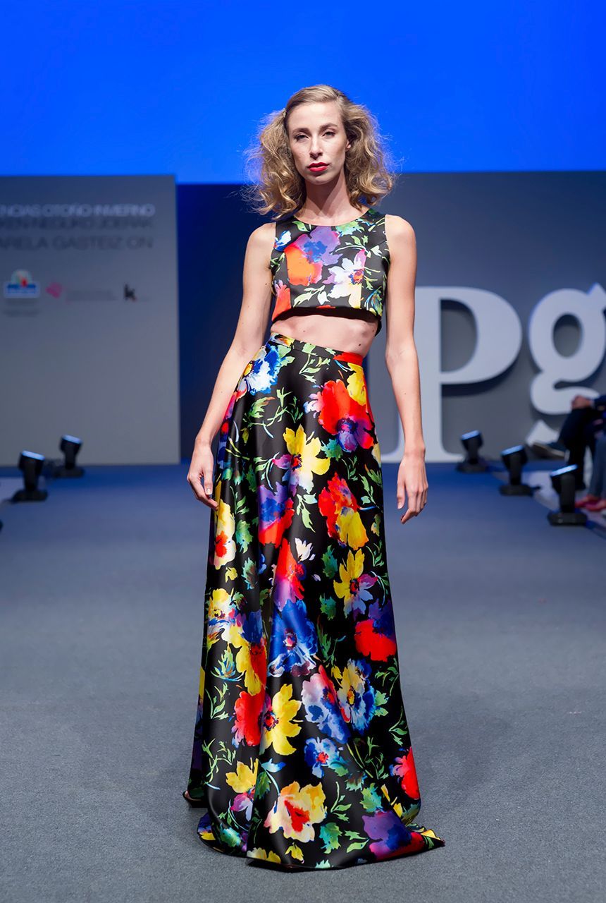 Una mujer camina por una pasarela con un vestido floral.