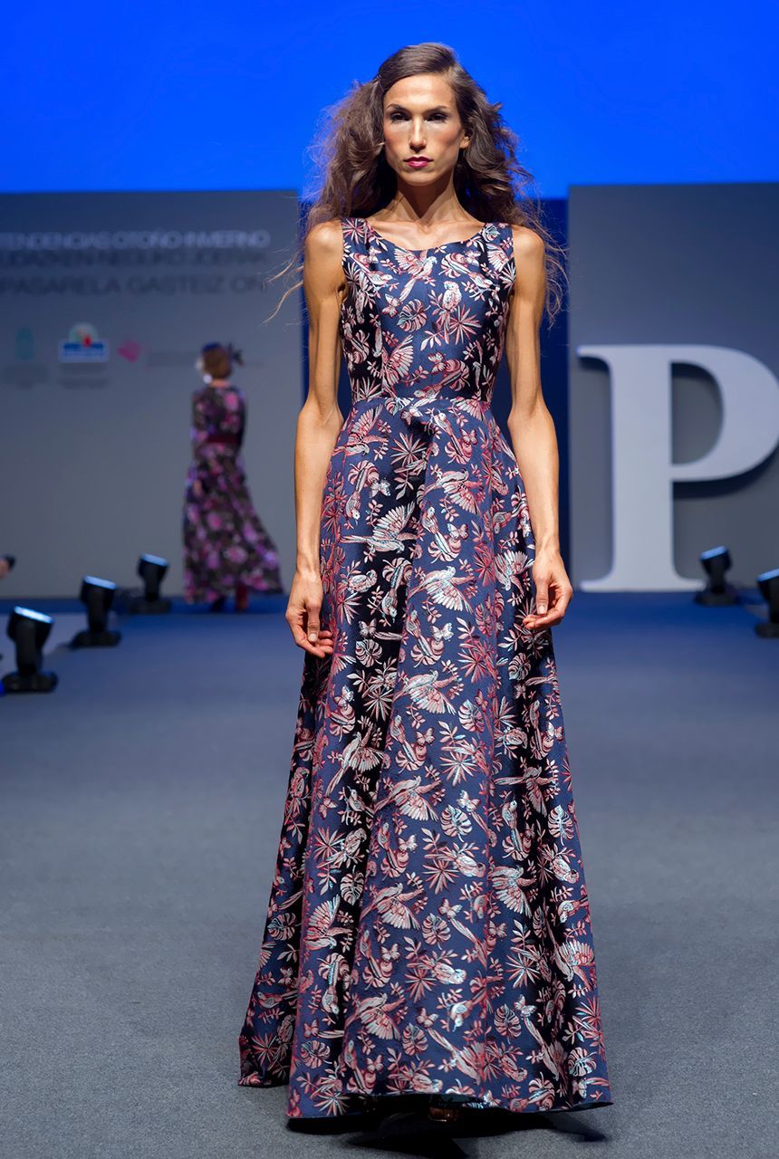 Una mujer camina por una pasarela con un vestido con la letra p en el fondo.