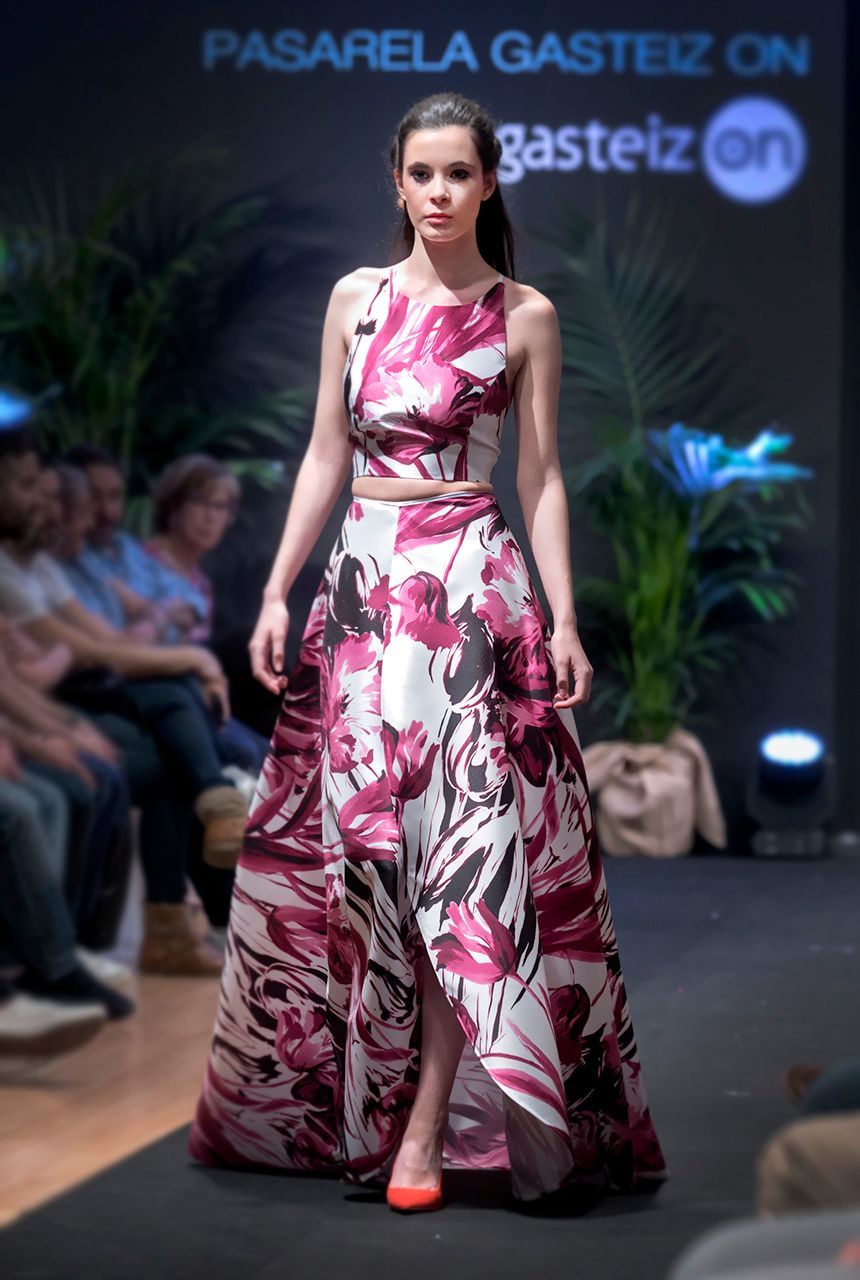 Una mujer camina por una pasarela con un vestido floral.