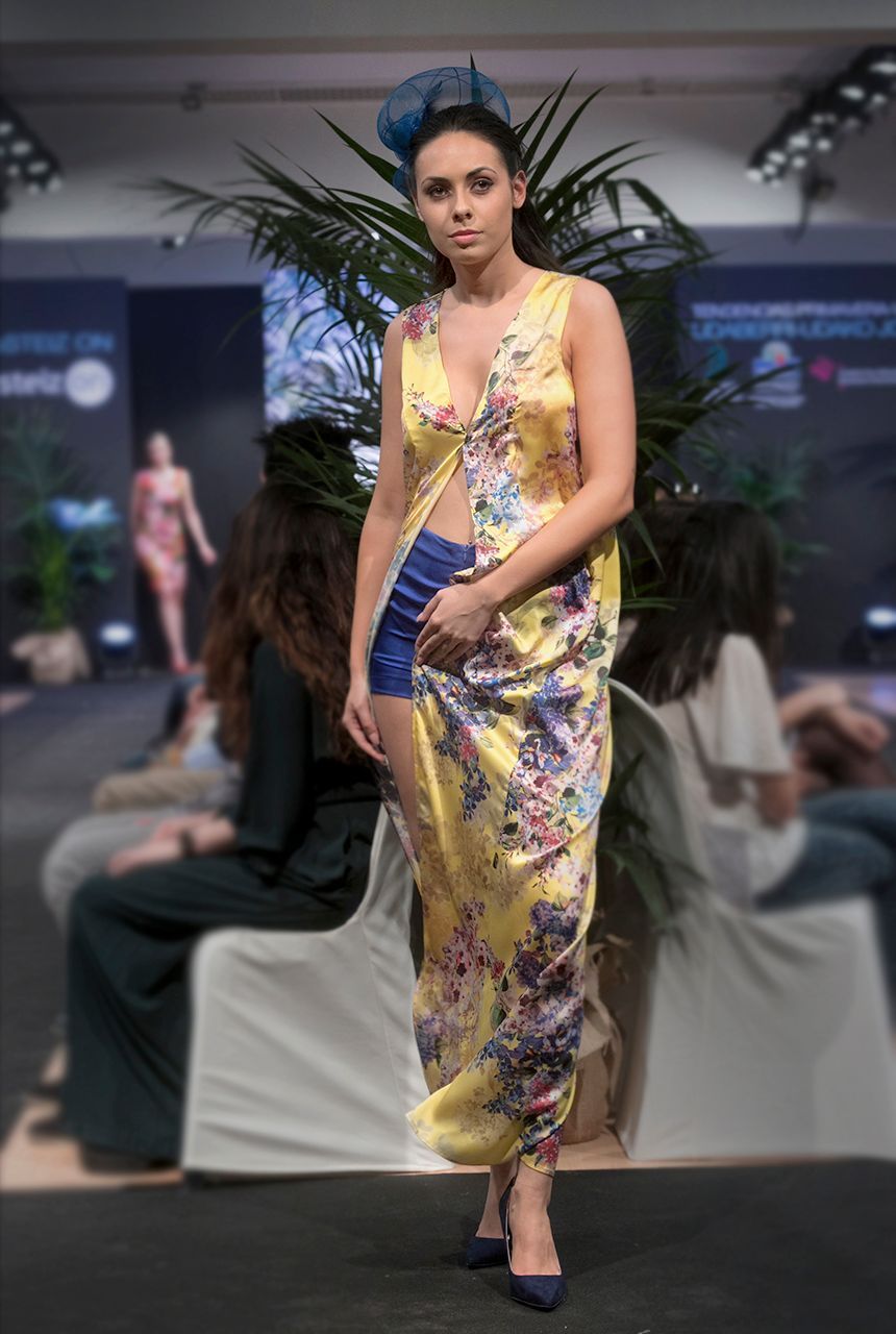 Una mujer camina por la pasarela de un desfile de moda con un vestido floral.