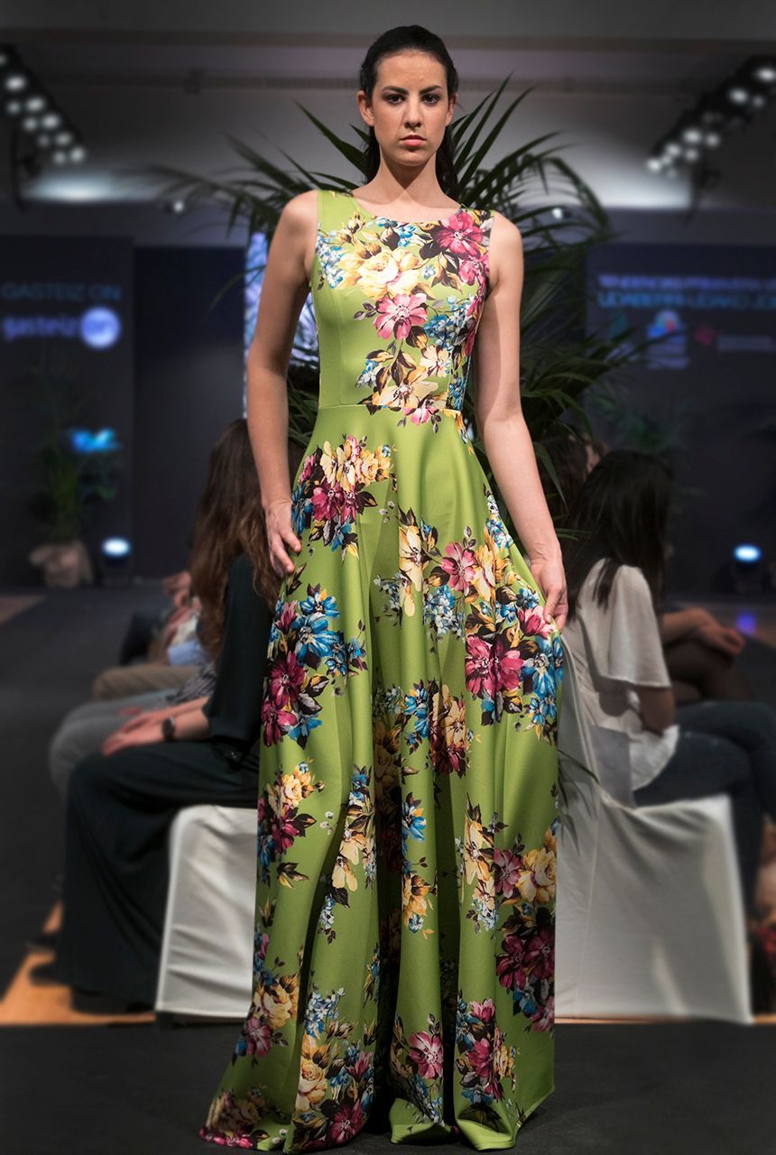 Una mujer está parada en una pasarela con un vestido floral verde.