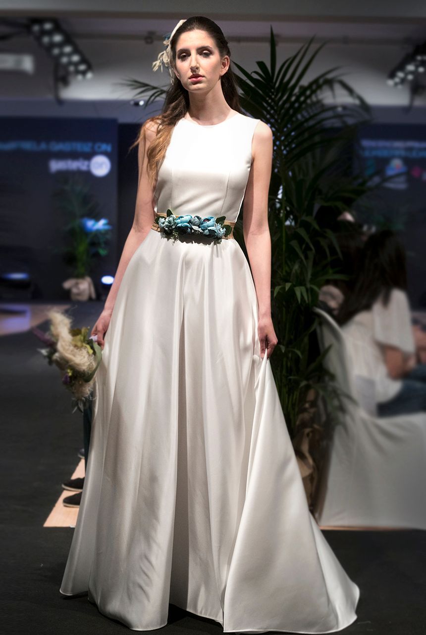 Una mujer con un vestido blanco camina por una pasarela.