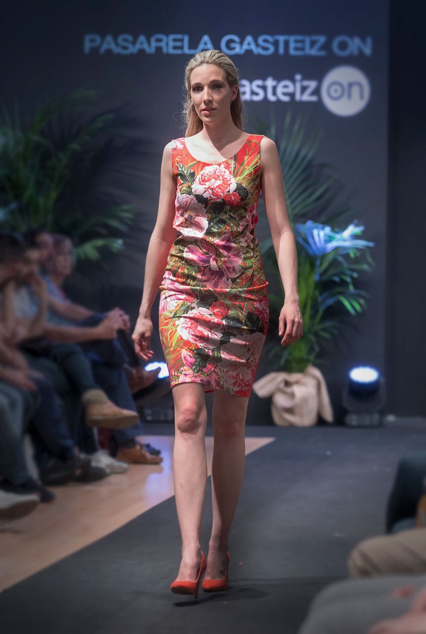 Una mujer camina por una pasarela con un vestido floral.